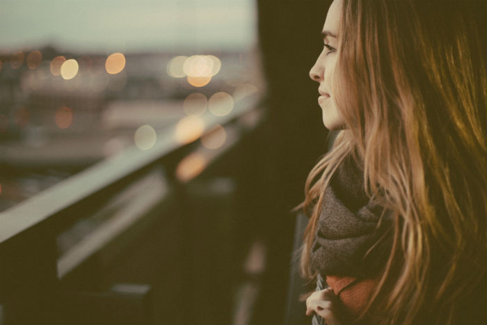 A smiling woman wearing a scarf, looking at city lights